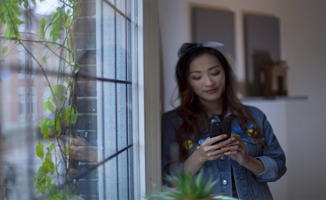 Vrouw bij raam op mobiel