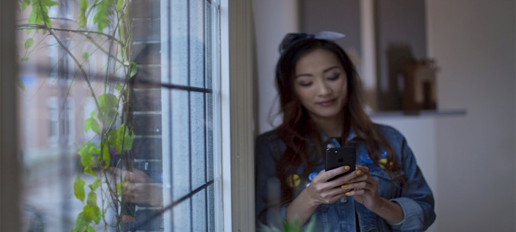Vrouw bij raam op mobiel
