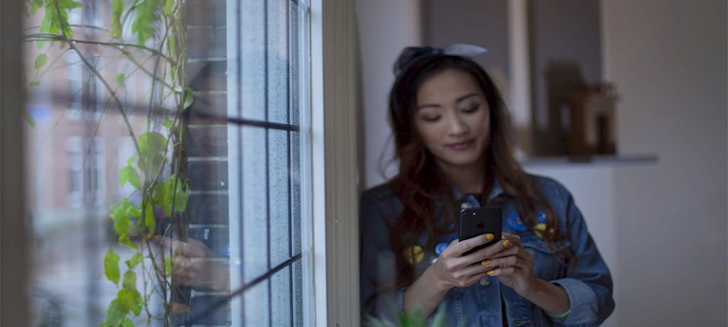 Vrouw bij raam op mobiel