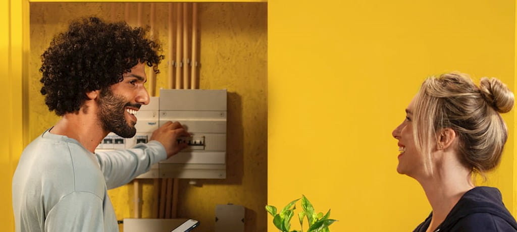 Dame en heer bij een meterkast in huis