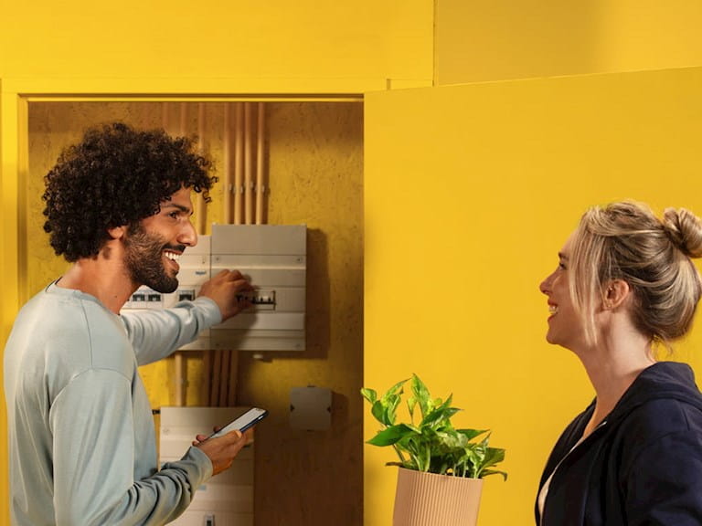 Dame en heer bij een meterkast in huis